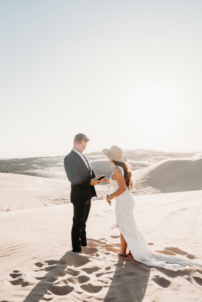 man and woman standing in sand dunes