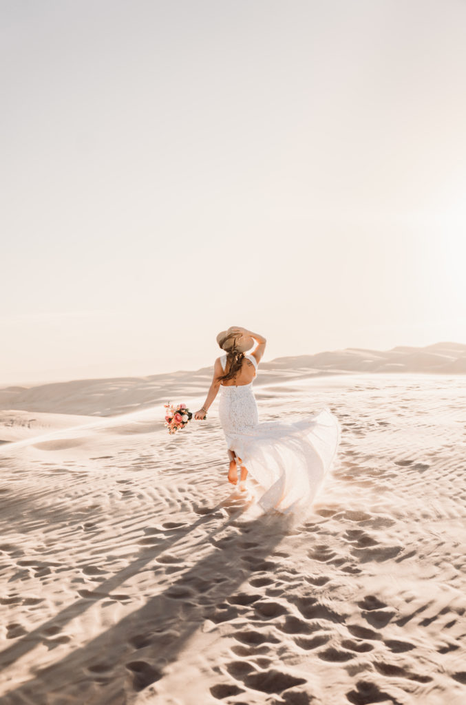 Bride walking in sand dunes in wedding dress