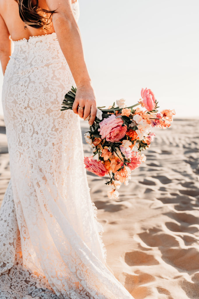 Bride holding bouquet in sand dunes