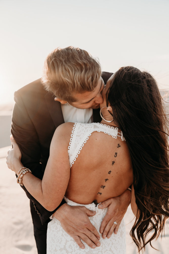 Groom kissing bride in Sand Dunes