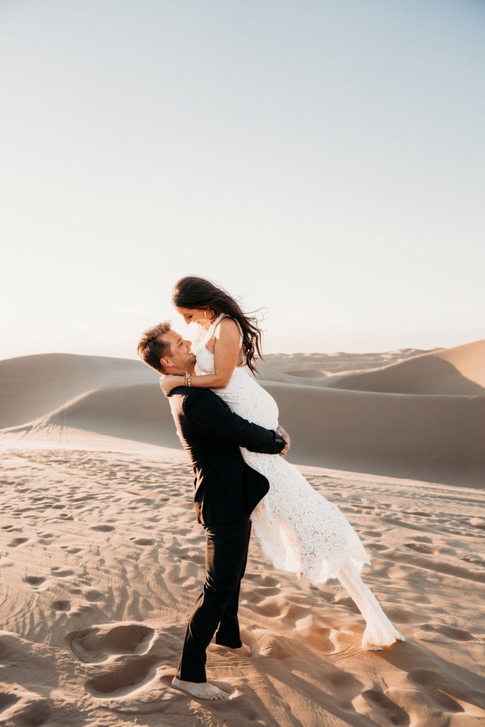 Groom picking up bride in Sand Dunes elopement
