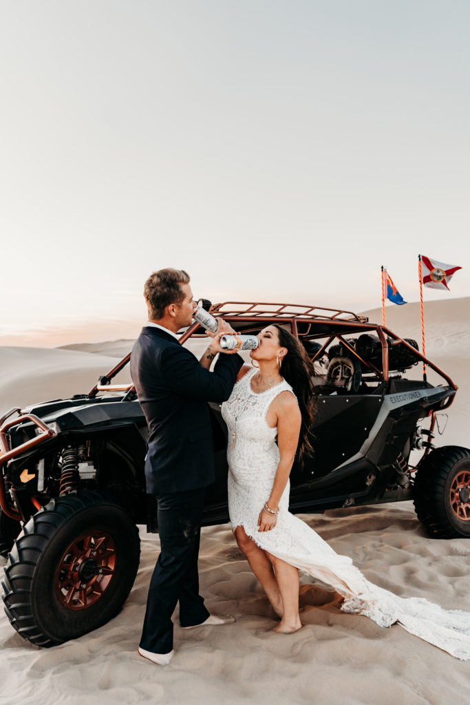 Bride and groom drinking white claw by UTV in sand dunes