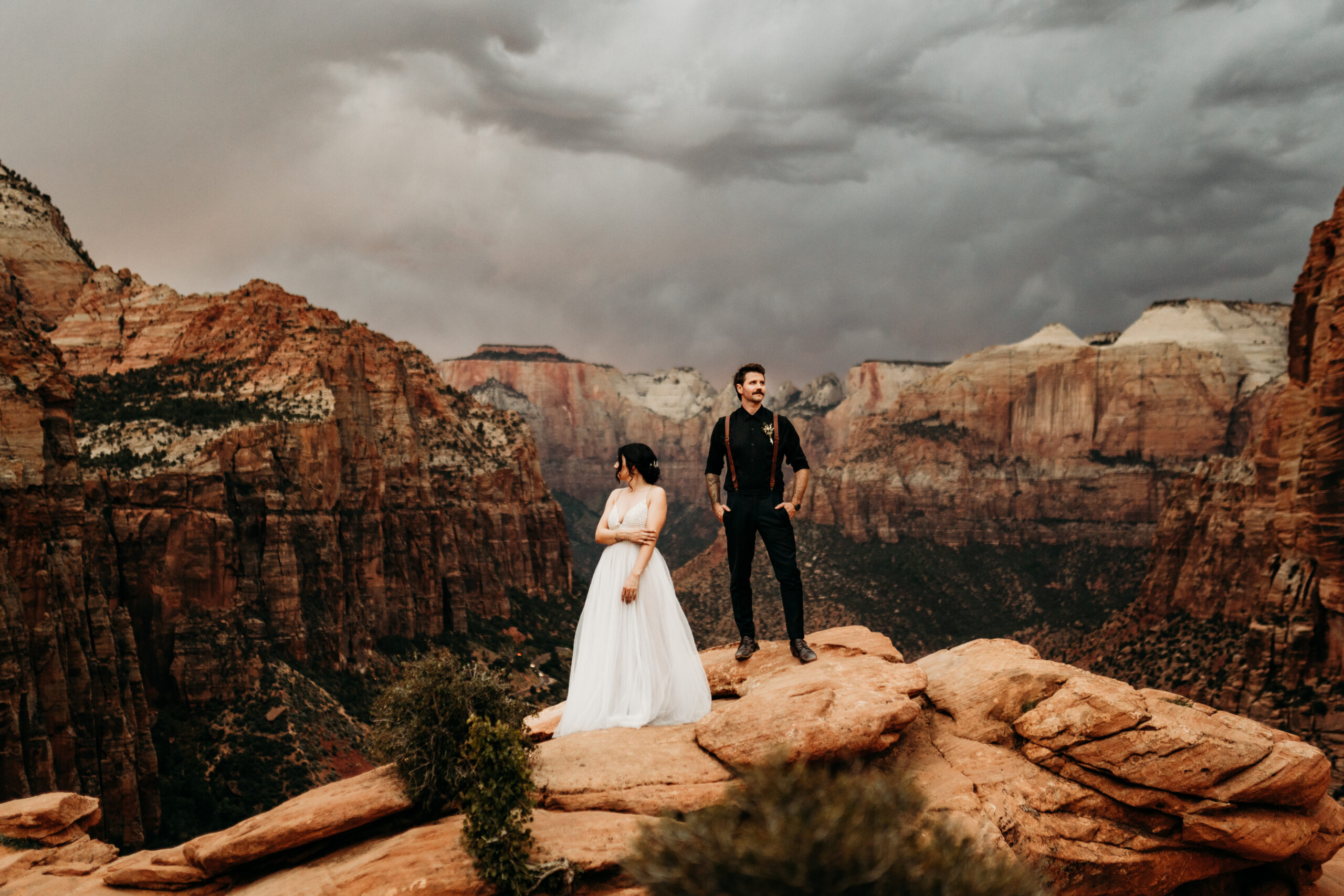 bride and groom at canyon overlook in zion national park on a stormy fall day