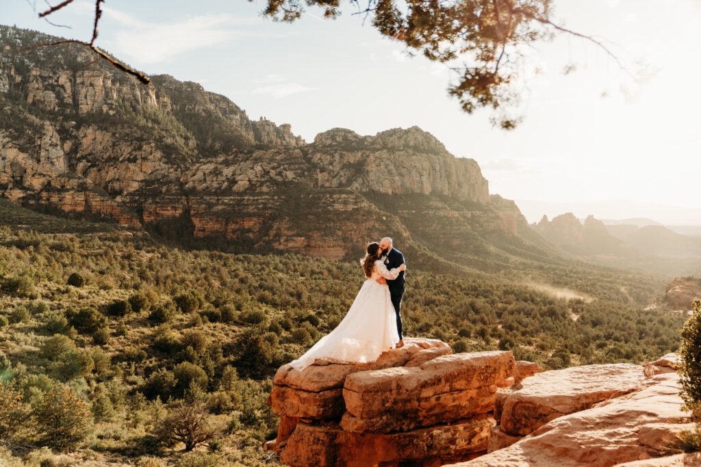 wedding couple kissing while standing on merry go round rock at sunset after their elopement in sedona arizona