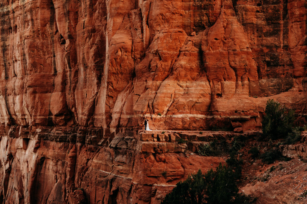 bride and groom standing on a ledge at Cathedral Rock in Sedona AZ on their elopement day 